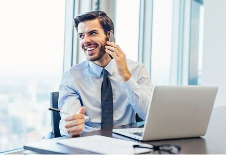 A smiling professional on the phone at his desk
